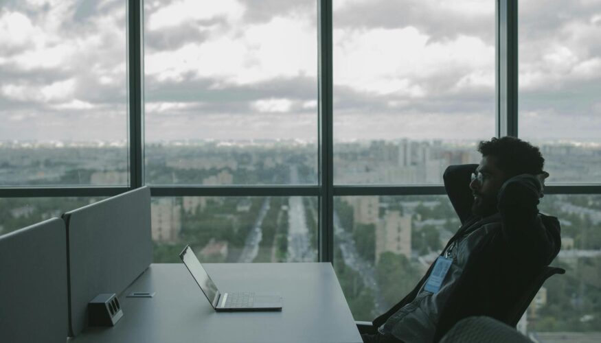 Man-relaxing-at-office-desk-with-city-view - Automated Incident Responses in Business Security