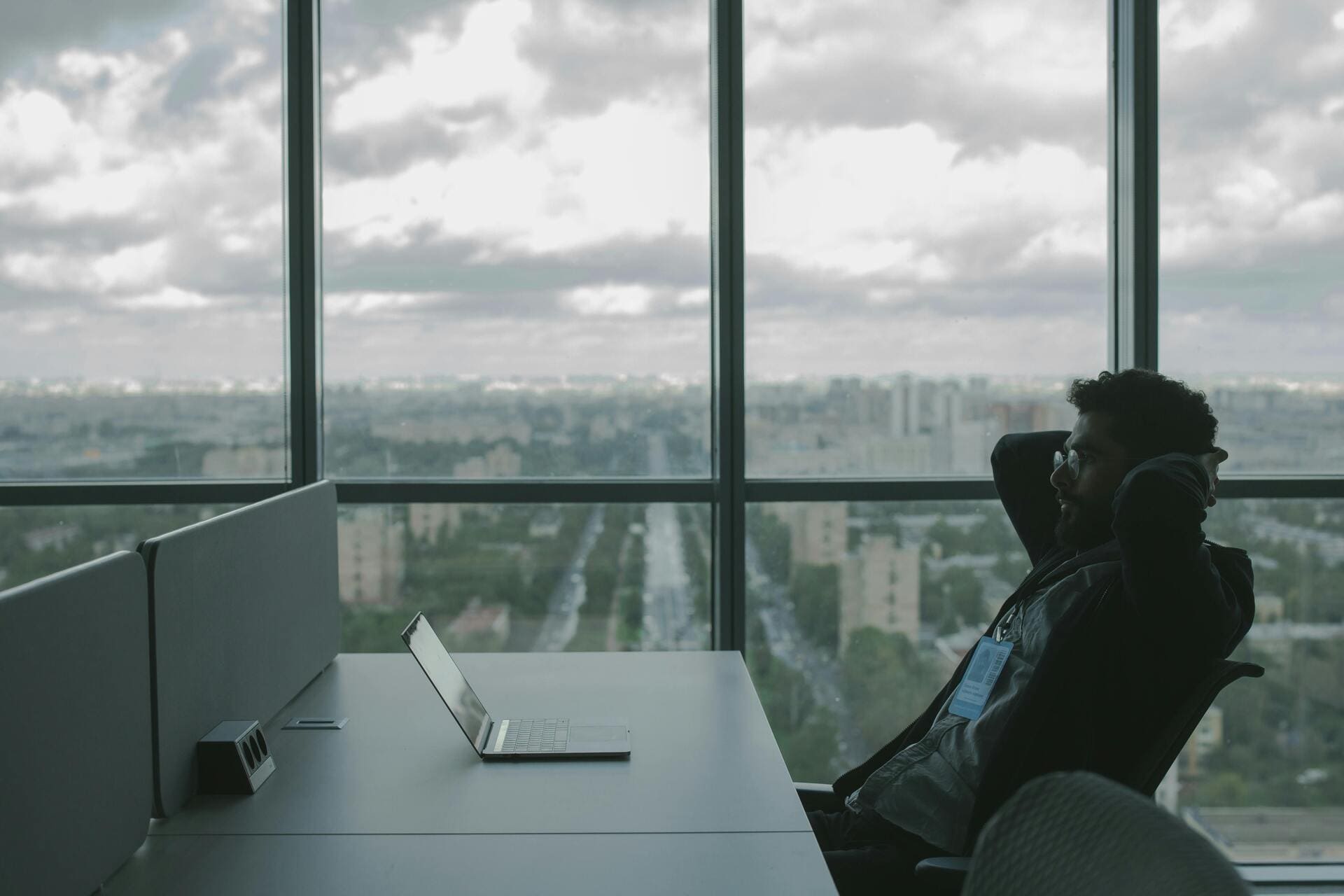 Man-relaxing-at-office-desk-with-city-view - Automated Incident Responses in Business Security
