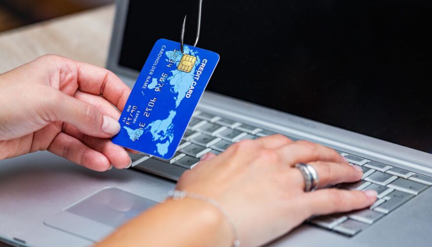 Credit-card-caught-on-phishing-hook-over-laptop-keyboard - Vishing and Phishing