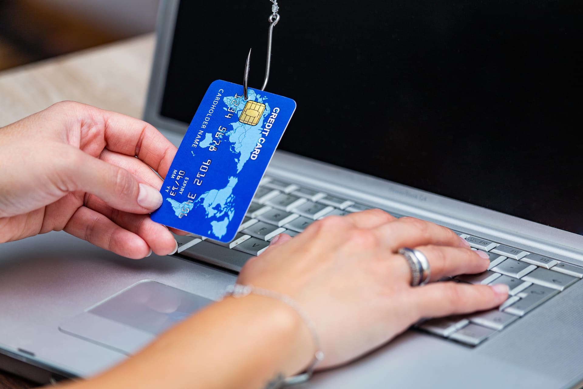 Credit-card-caught-on-phishing-hook-over-laptop-keyboard - Vishing and Phishing