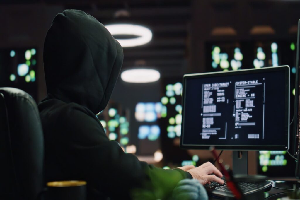 Hooded-hacker-working-at-a-computer-in-a-dark-room CMIT Cybersecurity Social Engineering