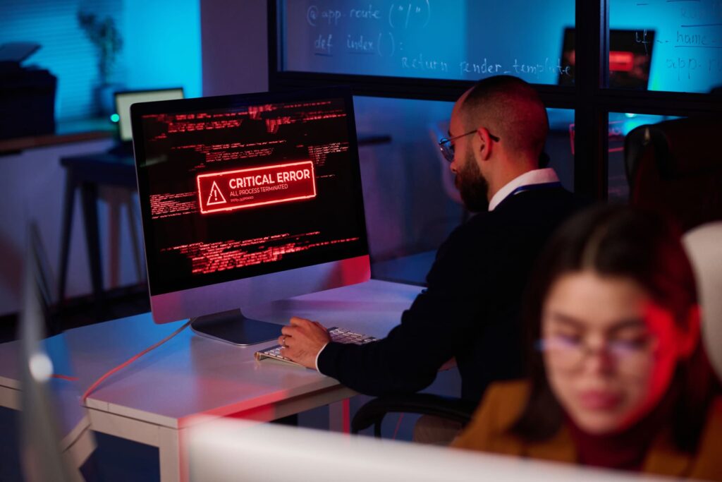 What is Malware in Cybersecurity? Technician-working-at-desk-with-critical-error-alert-on-monitor