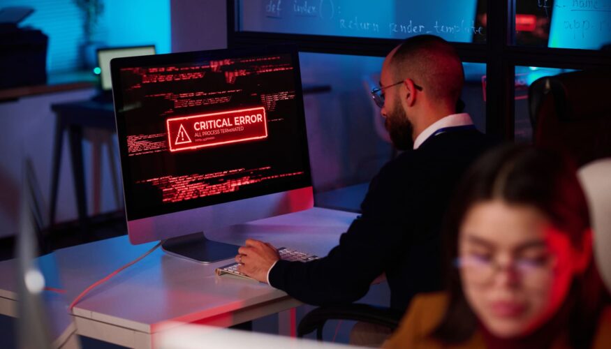 What is Malware in Cybersecurity? Technician-working-at-desk-with-critical-error-alert-on-monitor