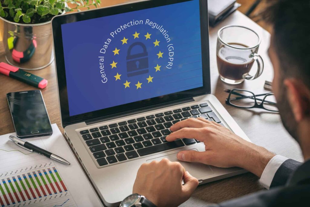 Person using a laptop displaying GDPR data protection graphic on screen