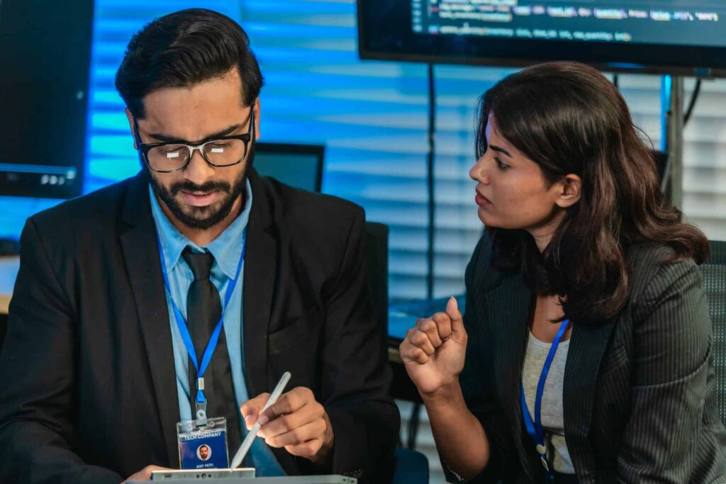Two colleagues in discussion one using a stylus on a tablet while the other listens - CMIT Solutions What Is PCI-DSS Compliance? Requirements, Checklist & More