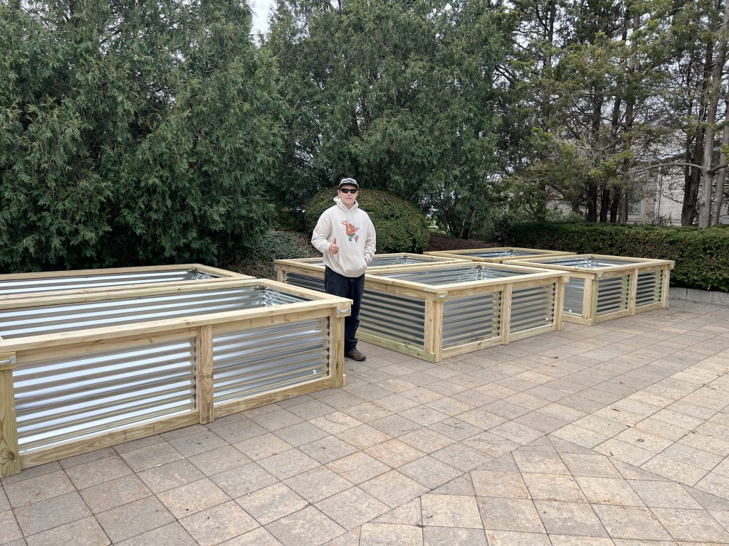 Tremper freshman Easton Stiner, now an Eagle Scout, pictured with the six garden beds he built for Kenosha's Shalom Center Community Garden